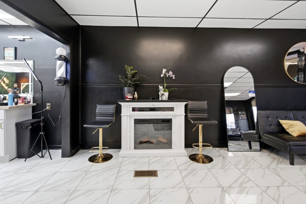 Front lounge at Golden Barbershop with a white fireplace and full length mirrors.
