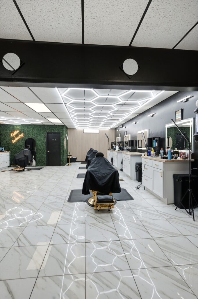 Barber station and lit mirror under hexagon ceiling lights at Golden Barbershop.