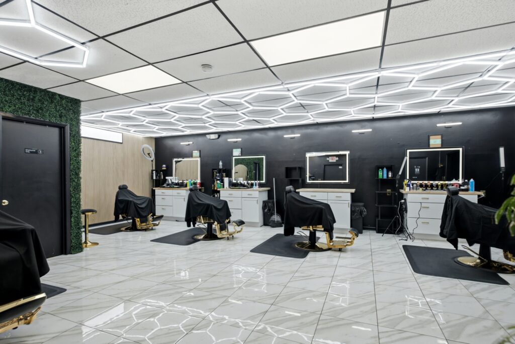 Main cutting floor at Golden Barbershop with barber stations under hexagon LED lighting.