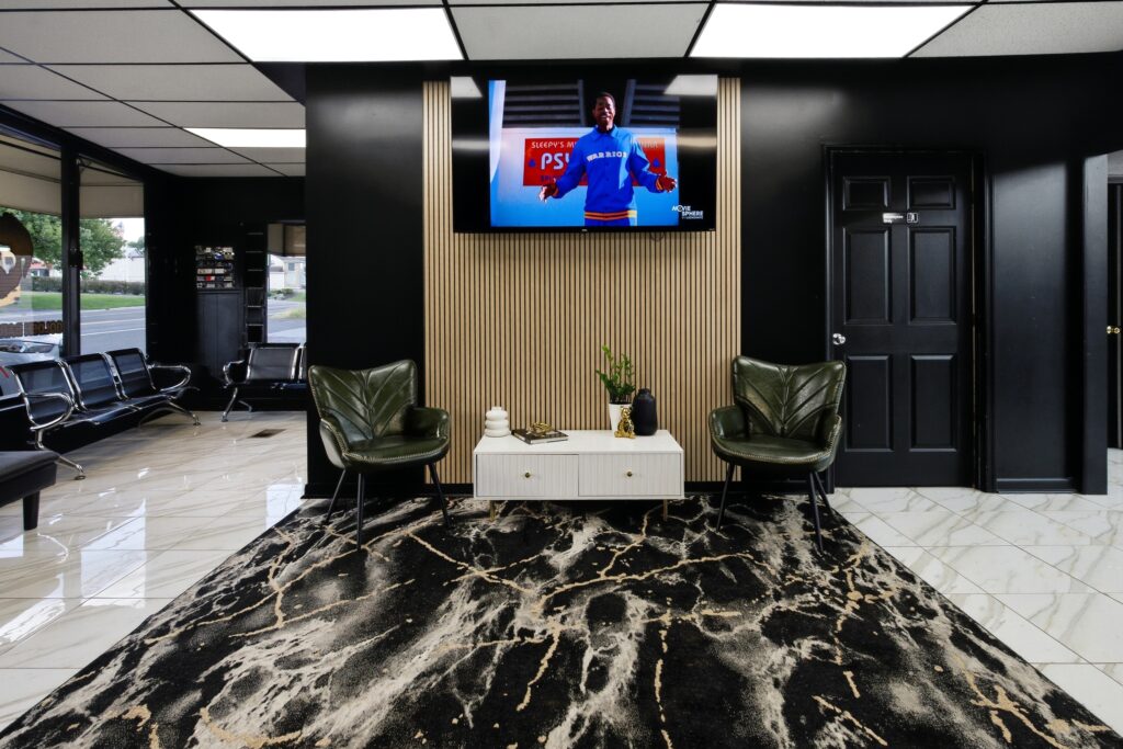 Waiting lounge at Golden Barbershop with green velvet chairs and a black and gold marble floor.