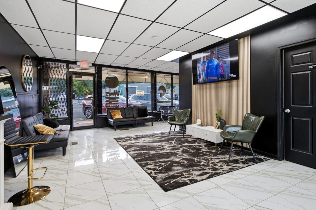 Waiting area at Golden Barbershop with street facing windows and leather seating.