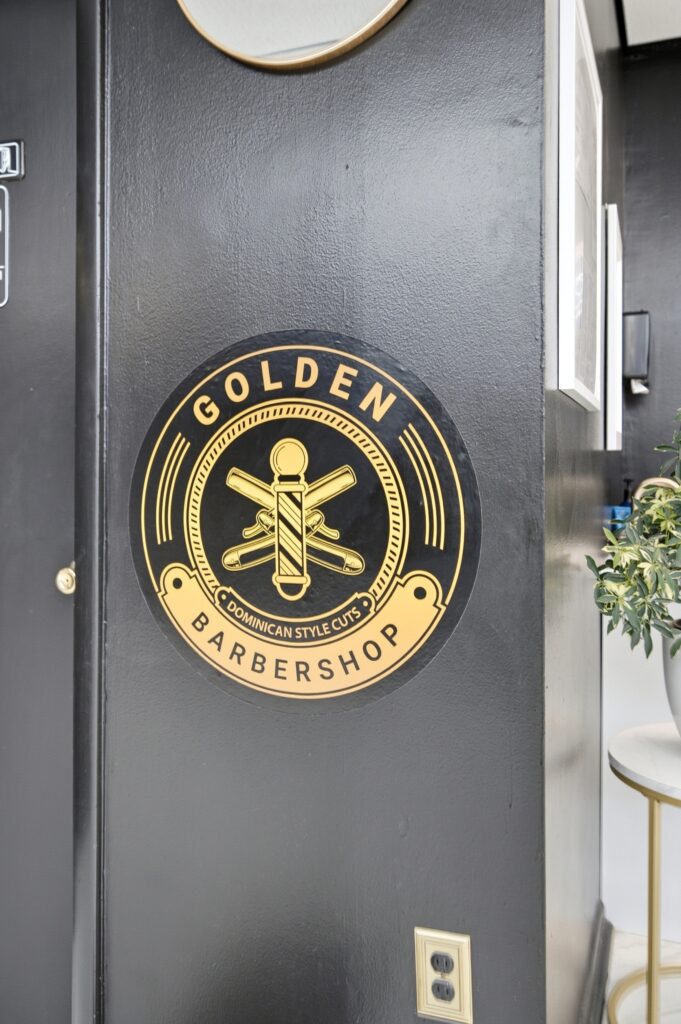 Golden Barbershop gold logo medallion mounted on the shop door.